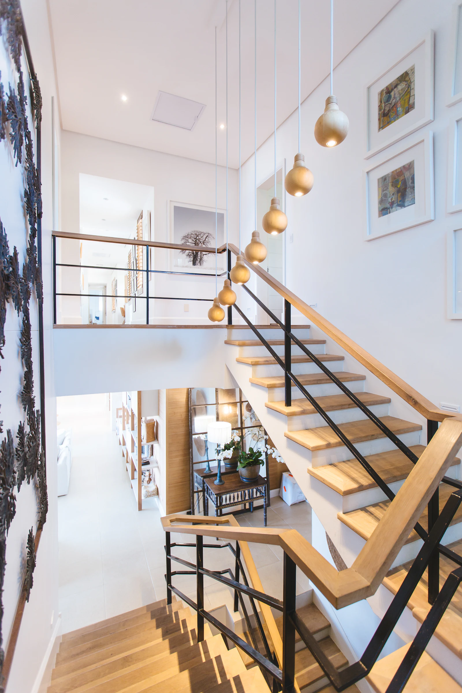 Oak staircase with black steel balustrade rising to a loft
