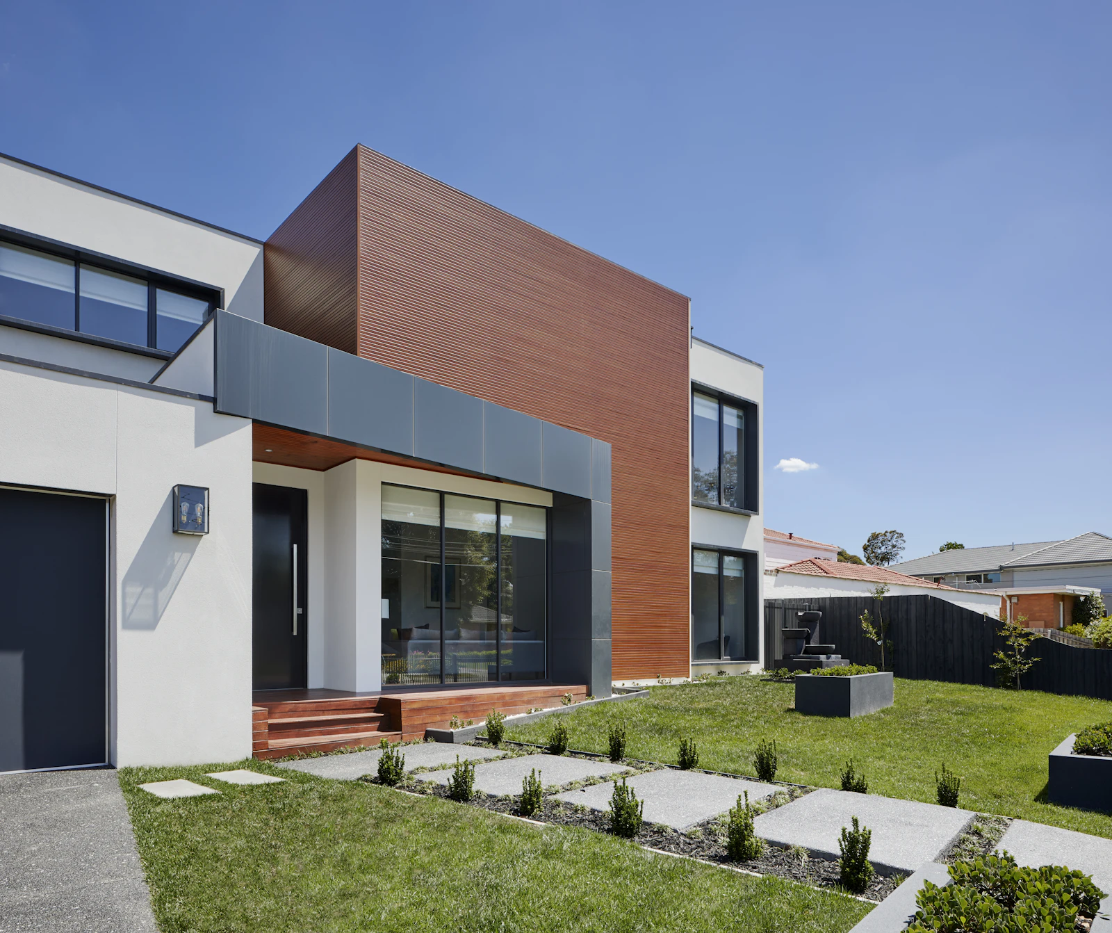 Two-storey house with copper-toned cladding and grey render