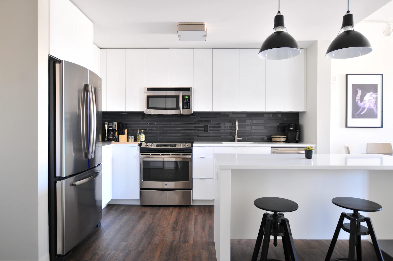Bright kitchen with white cabinetry, pendant lights and bar stools
